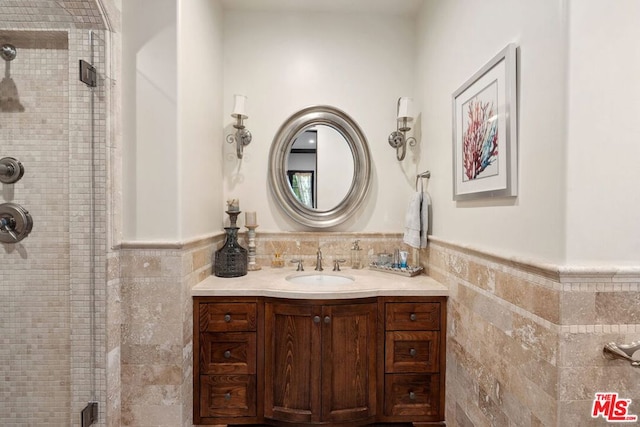 bathroom featuring vanity, a shower with door, and tile walls