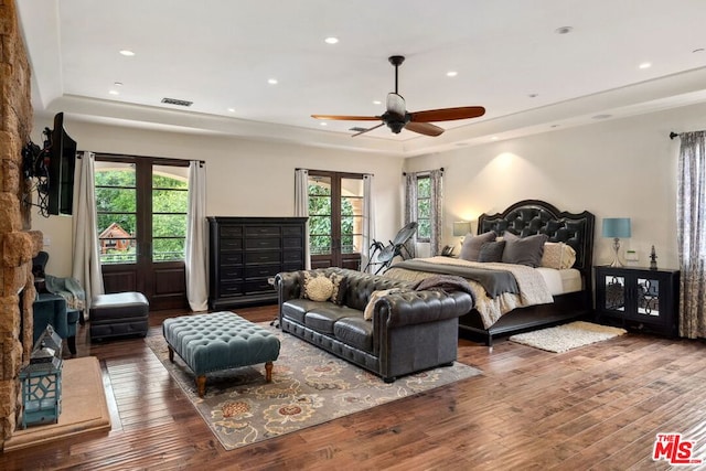 bedroom featuring a tray ceiling, dark wood-type flooring, french doors, and ceiling fan