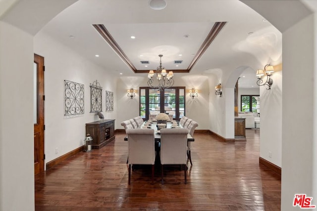 dining area featuring a raised ceiling, crown molding, a notable chandelier, and dark hardwood / wood-style flooring