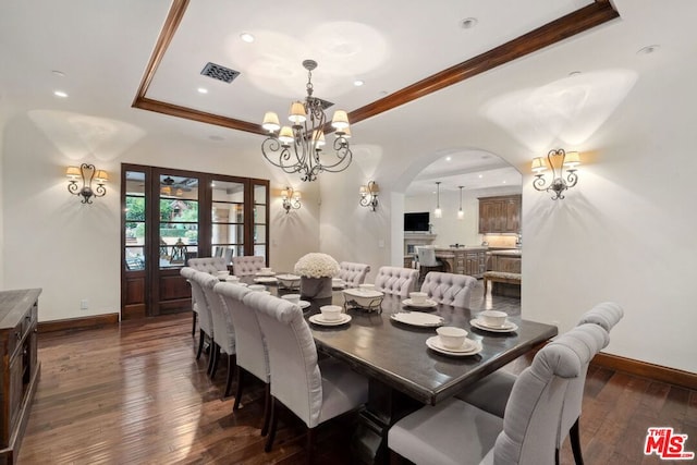 dining area featuring dark hardwood / wood-style flooring, a notable chandelier, crown molding, and a raised ceiling