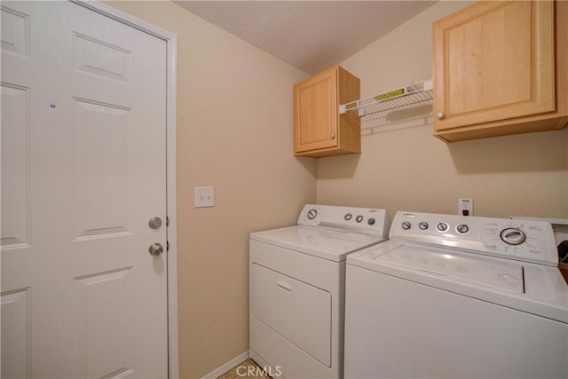 clothes washing area featuring cabinets and washer and dryer