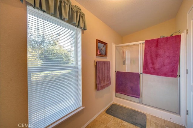 bathroom with vaulted ceiling, a shower with shower door, and tile patterned flooring