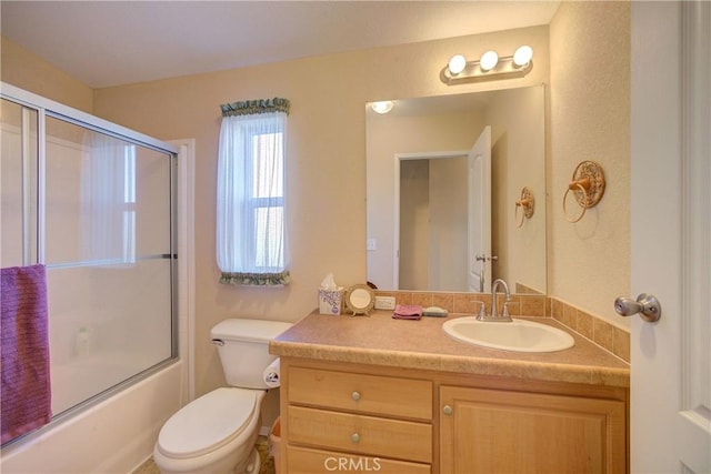 full bathroom with vanity, bath / shower combo with glass door, and toilet