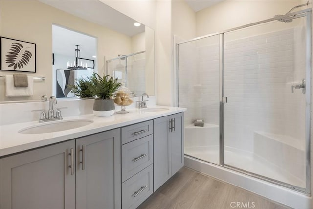 bathroom featuring vanity, hardwood / wood-style floors, an inviting chandelier, and walk in shower