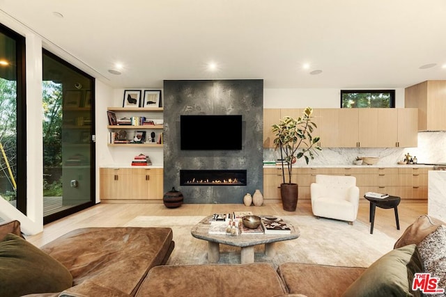 living room with floor to ceiling windows, light wood-type flooring, a wealth of natural light, and a fireplace