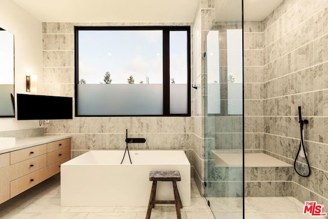 bathroom featuring vanity, plus walk in shower, and tile walls