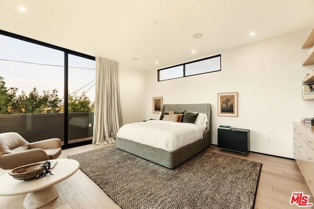 bedroom with access to exterior, light hardwood / wood-style floors, and floor to ceiling windows