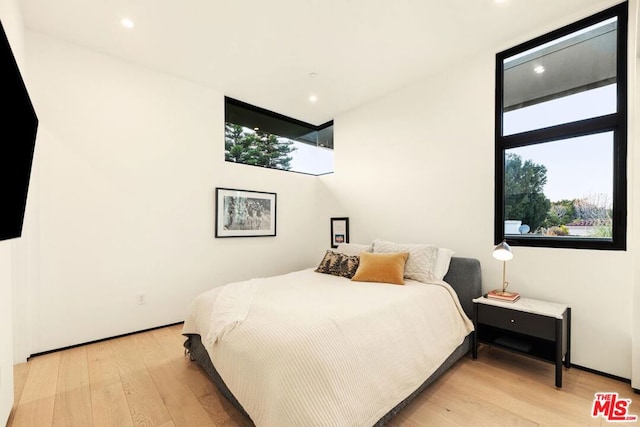 bedroom with multiple windows and light hardwood / wood-style flooring