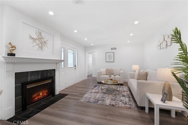 living room with dark hardwood / wood-style flooring and a tiled fireplace