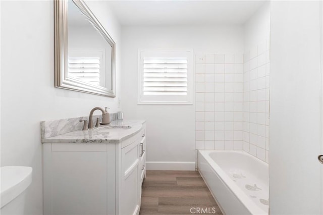 full bathroom with tiled shower / bath, vanity, toilet, and hardwood / wood-style floors