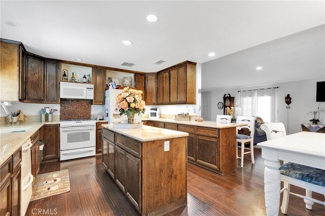 kitchen featuring white appliances, dark hardwood / wood-style floors, sink, and a kitchen island