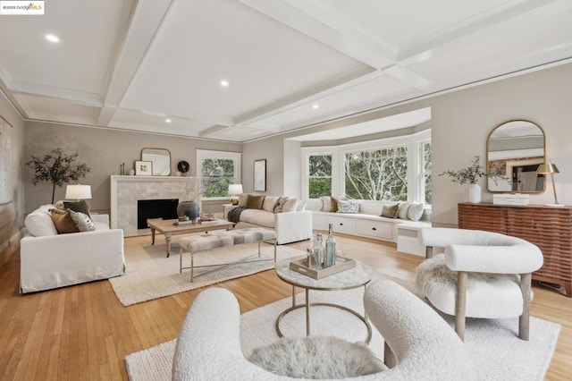 living room with coffered ceiling, beam ceiling, light hardwood / wood-style flooring, and a premium fireplace