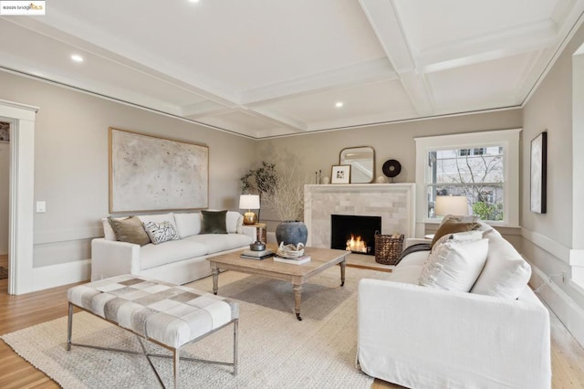 living room featuring beamed ceiling, coffered ceiling, a fireplace, and light wood-type flooring