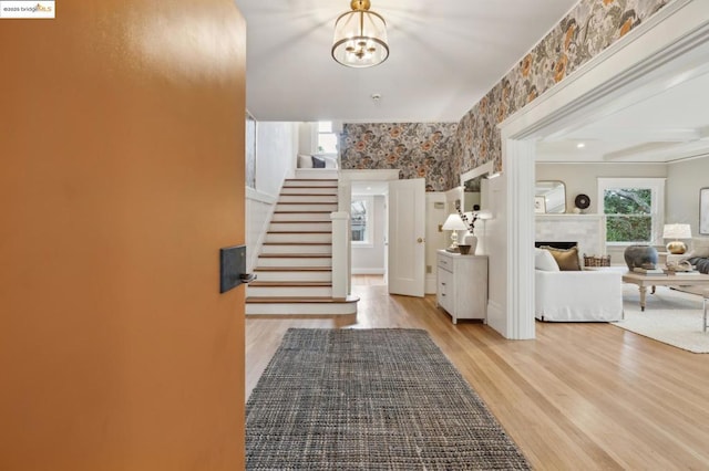 entrance foyer featuring a tile fireplace, a notable chandelier, and light hardwood / wood-style flooring