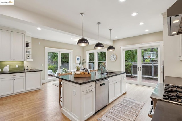 kitchen with french doors, stainless steel dishwasher, white cabinetry, and an island with sink