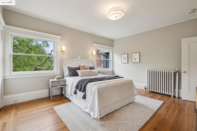 bedroom with radiator heating unit and hardwood / wood-style floors