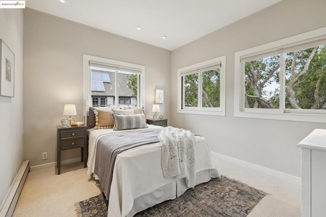 bedroom with a baseboard heating unit and light colored carpet