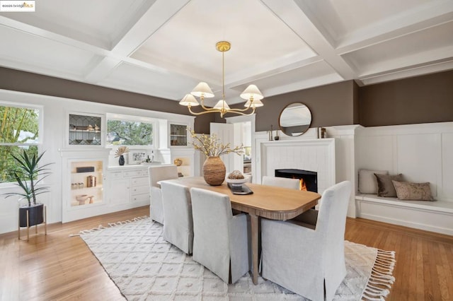 dining room featuring coffered ceiling, a notable chandelier, beam ceiling, and light wood-type flooring