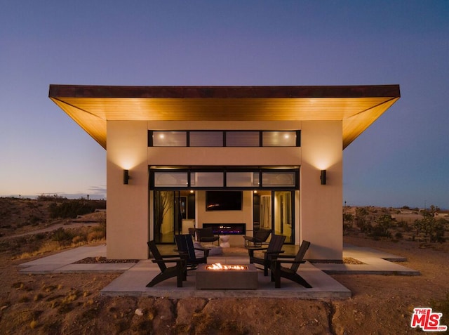 back house at dusk with a patio area and an outdoor fire pit