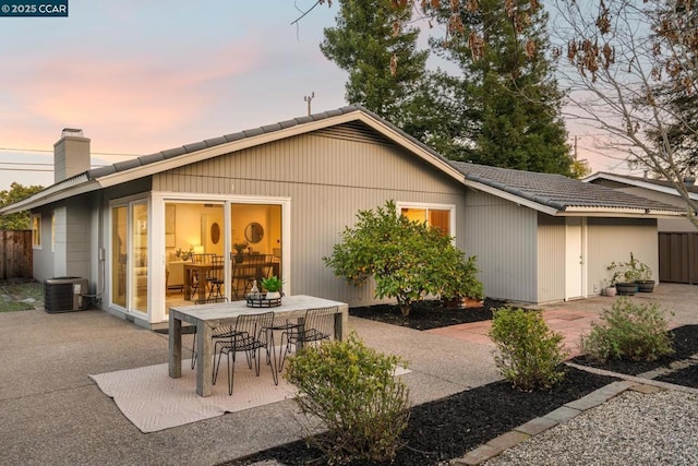 back house at dusk featuring cooling unit and a patio area