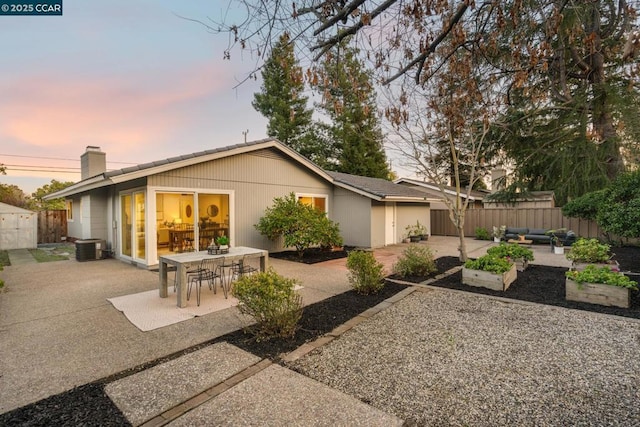 back house at dusk featuring cooling unit and a patio area