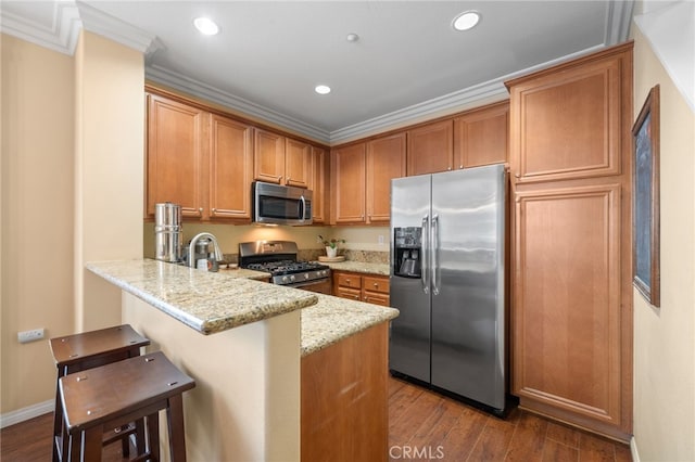 kitchen featuring stainless steel appliances, dark hardwood / wood-style floors, light stone counters, a kitchen bar, and kitchen peninsula