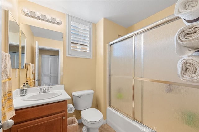 full bathroom with vanity, bath / shower combo with glass door, and toilet