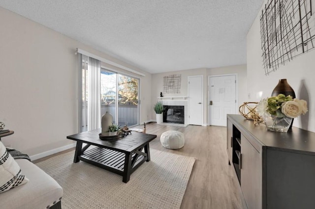 living room featuring a textured ceiling, a fireplace, and light hardwood / wood-style floors