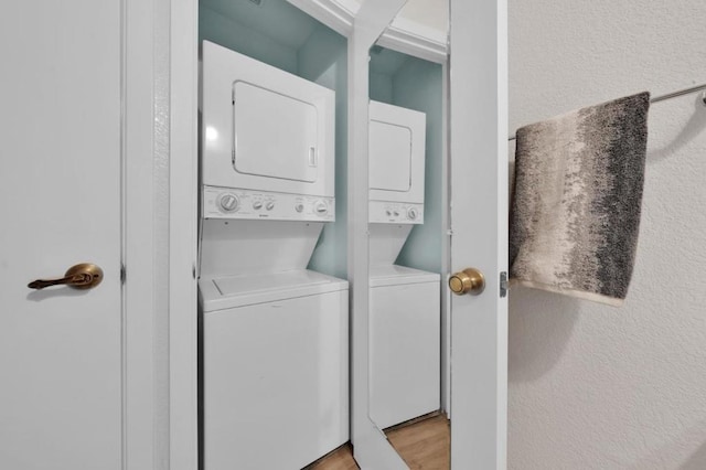 clothes washing area with stacked washing maching and dryer and light wood-type flooring