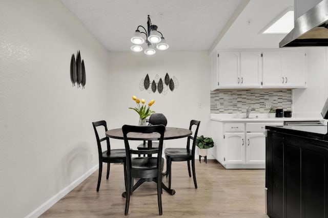 dining area with a chandelier, sink, and light hardwood / wood-style flooring