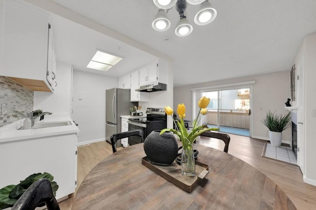 dining area featuring sink, a chandelier, and light hardwood / wood-style floors