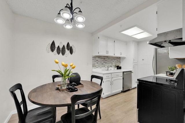 dining space featuring sink, a chandelier, light hardwood / wood-style floors, and a textured ceiling