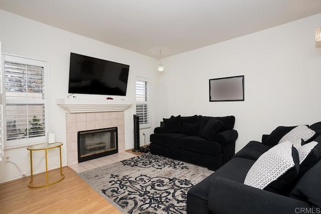 living room featuring a tile fireplace and light wood-type flooring