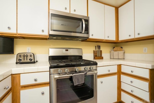 kitchen featuring stainless steel appliances, tile countertops, and white cabinets