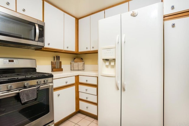 kitchen featuring stainless steel appliances, light tile patterned floors, and white cabinets