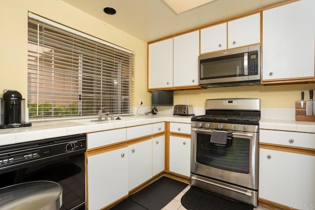 kitchen with stainless steel appliances, white cabinetry, and sink