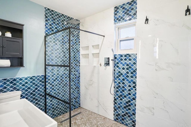 bathroom with tiled shower and sink