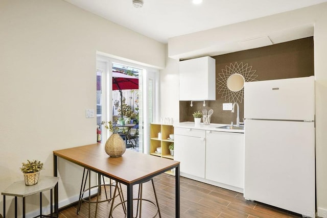 kitchen featuring white refrigerator, sink, white cabinets, and decorative backsplash