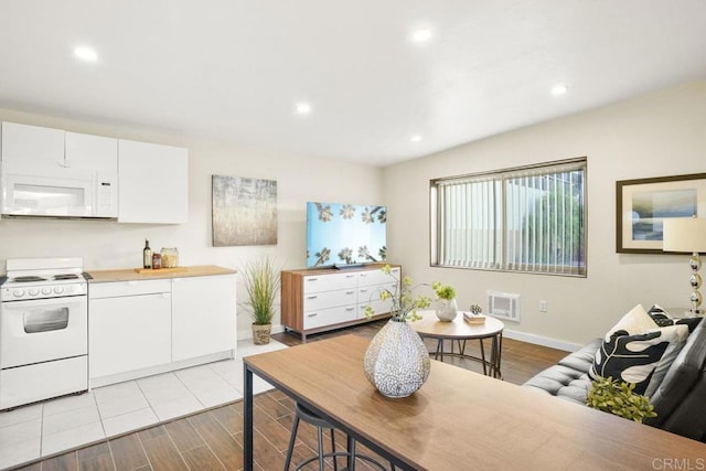 kitchen featuring butcher block countertops, white appliances, light hardwood / wood-style flooring, and white cabinets