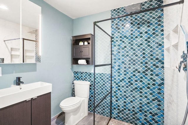 bathroom featuring vanity, toilet, and a tile shower