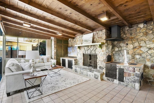 living room featuring beamed ceiling, light tile patterned flooring, a stone fireplace, and wood ceiling