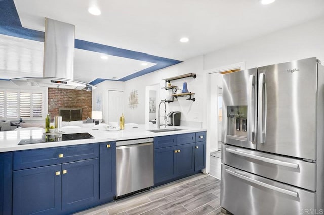 kitchen featuring appliances with stainless steel finishes, sink, island range hood, and blue cabinetry