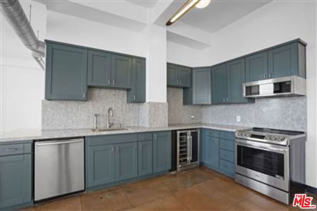 kitchen with sink, beverage cooler, backsplash, dark tile patterned floors, and stainless steel appliances