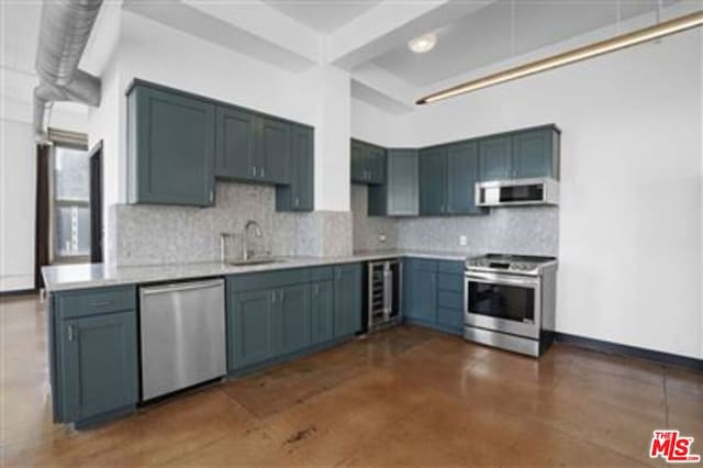 kitchen with tasteful backsplash, appliances with stainless steel finishes, sink, and beverage cooler