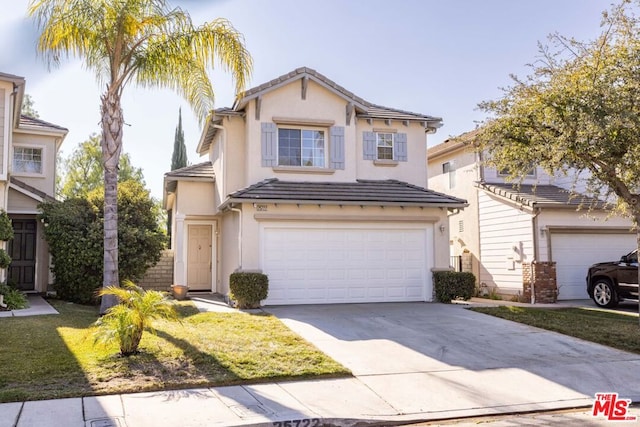 view of property featuring a garage and a front lawn