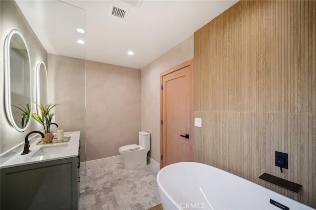 bathroom with vanity, a tub to relax in, and toilet