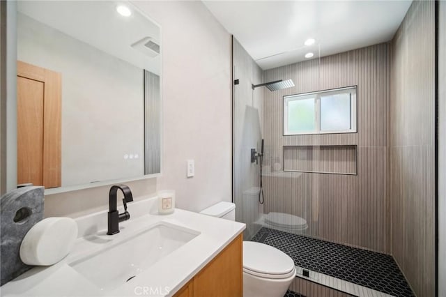 bathroom with vanity, toilet, and a tile shower