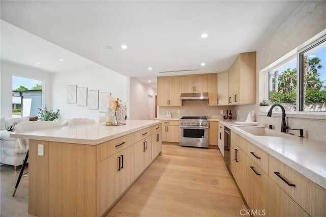 kitchen with a kitchen bar, light brown cabinetry, sink, a kitchen island, and stainless steel appliances