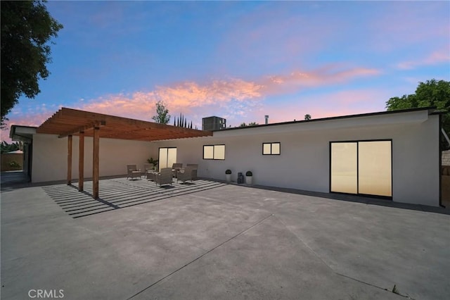 back house at dusk with an outdoor living space, a pergola, and a patio