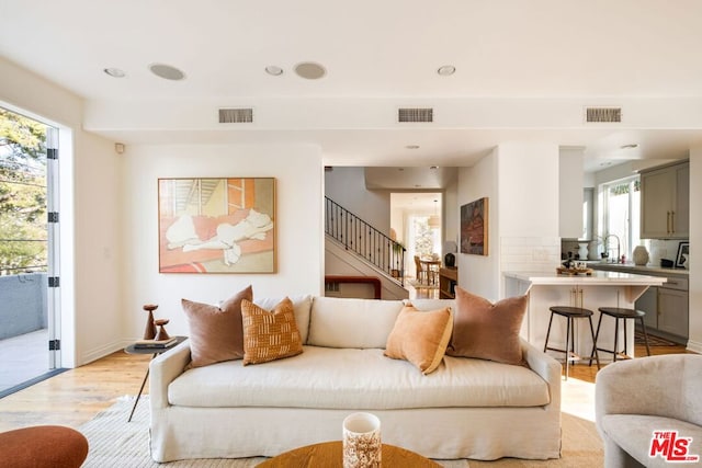 living room featuring sink and light hardwood / wood-style flooring